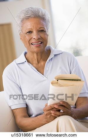 Stock Image - Woman relaxing with a book and smiling. Fotosearch