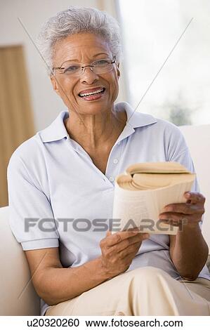 Stock Image - Woman relaxing with a book and smiling. Fotosearch