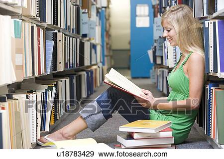Woman sitting on floor in library reading book View Large Photo Image Stock Photo - Woman sitting on floor in library reading book. Fotosearch