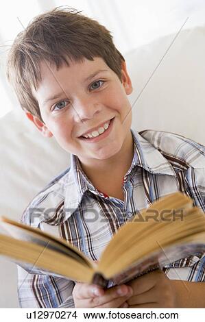 Young Boy Sitting On A Sofa Reading A Book View Large Photo Image Picture - Young Boy Sitting On A Sofa Reading A Book. Fotosearch