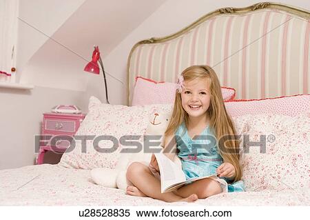 Young girl sitting on bed with book smiling View Large Photo Image Stock Photography - Young girl sitting on bed with book smiling. Fotosearch