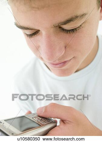 Teenage boy using cellular phone and smiling View Large Photo Image Stock Image - Teenage boy using cellular phone and smiling. Fotosearch