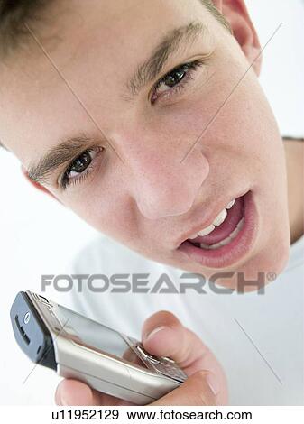 Stock Photo - Teenage boy using cellular phone and looking mad. Fotosearch