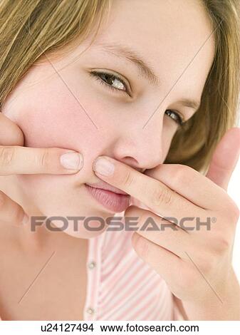 Picture - Teenage girl popping zit on face. Fotosearch