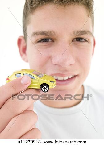 Stock Photo - Young boy holding toy car and smiling. Fotosearch