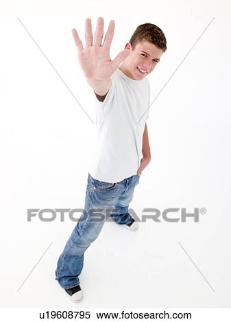 Stock Photography - Teenage boy standing with hand up smiling. Fotosearch