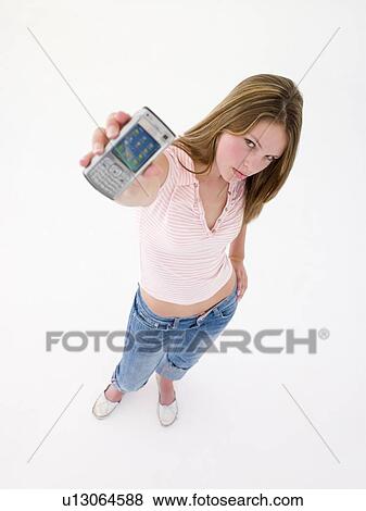 Stock Photo - Teenage girl holding up cellular phone and frowning. Fotosearch
