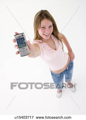 Stock Photo - Teenage girl holding up cellular phone and smiling. Fotosearch