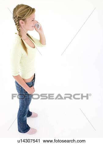 Stock Image - Teenage girl using cellular phone and smiling. Fotosearch