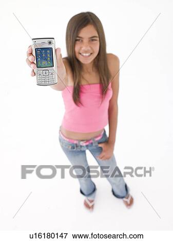 Young girl holding up cellular phone and smiling View Large Photo Image Stock Photo - Young girl holding up cellular phone and smiling. Fotosearch