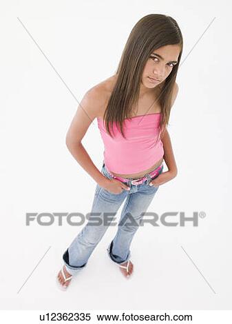 Stock Photography - Young girl standing with hands in pockets frowning. Fotosearch
