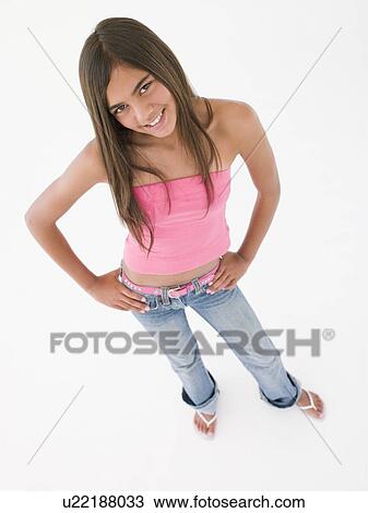 Stock Image - Young girl standing with hands on hips smiling. Fotosearch