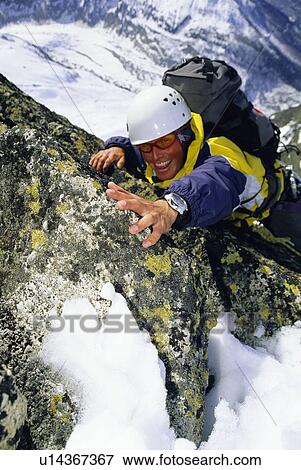 Mountain climber coming up snowy mountain smiling (selective focus) View Large Photo Image Stock Photo - Mountain climber coming up snowy mountain smiling (selective focus). Fotosearch