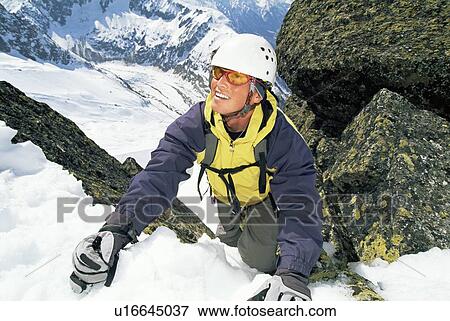 Mountain climber coming up snowy mountain smiling (selective focus) View Large Photo Image Stock Photo - Mountain climber coming up snowy mountain smiling (selective focus). Fotosearch