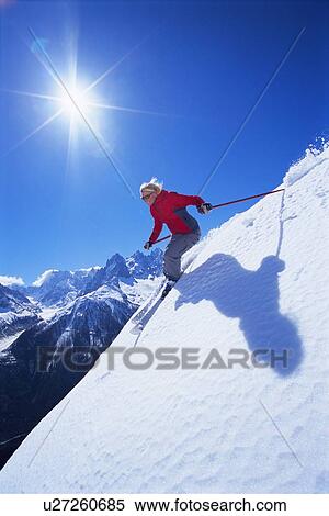 Stock Photography - Skier coming down snowy hill smiling (lens flare). Fotosearch