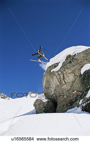 Skier jumping off cliff (far away) View Large Photo Image Picture - Skier jumping off cliff (far away). Fotosearch