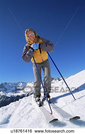 Stock Photograph - Skier standing on hill smiling. Fotosearch