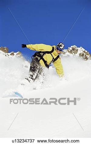 Stock Photo - Snowboarder coming down hill smiling. Fotosearch