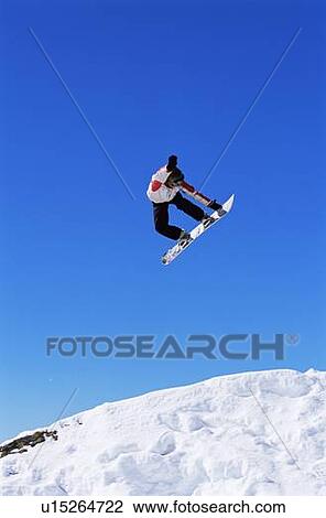 Stock Image - Snowboarder doing jump on hill. Fotosearch