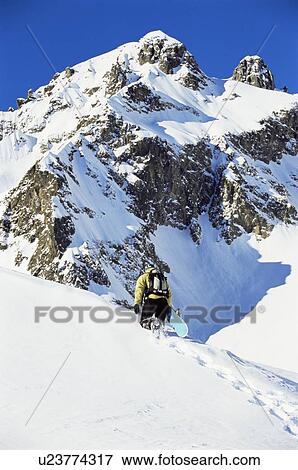 Snowboarder going up hill carrying board View Large Photo Image Stock Photo - Snowboarder going up hill carrying board. Fotosearch