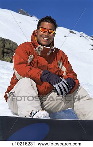 Snowboarder sitting on hill with board smiling (selective focus) View Large Photo Image Stock Image - Snowboarder sitting on hill with board smiling (selective focus). Fotosearch