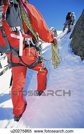 Stock Photography - Two mountain climbers going up snowy mountain (selective focus). Fotosearch