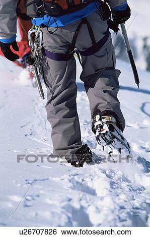Stock Photograph - Two mountain climbers walking in snow (selective focus). Fotosearch