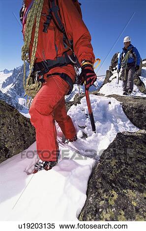 Stock Photography - Two mountain climbers walking in snow (selective focus). Fotosearch