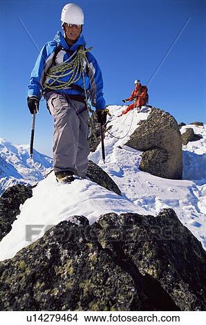 Two mountain climbers walking on snowy rocks (selective focus) View Large Photo Image Picture - Two mountain climbers walking on snowy rocks (selective focus). Fotosearch
