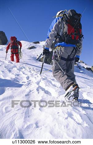 Two mountain climbers walking up snowy mountain (selective focus) View Large Photo Image Stock Photograph - Two mountain climbers walking up snowy mountain (selective focus). Fotosearch