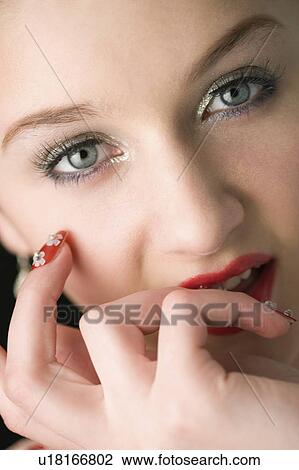 Stock Image - Studio shot of teenage girl with makeup and artificial fingernails. Fotosearch