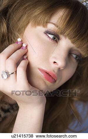 Stock Photo - Studio shot of teenage girl with makeup and hand on chin. Fotosearch