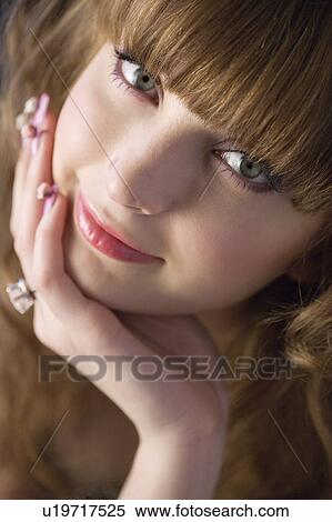 Stock Photography - Studio shot of teenage girl with makeup and hand on chin. Fotosearch
