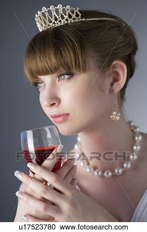 Stock Image - Teenage girl wearing jewelries holding a glass of wine. Fotosearch