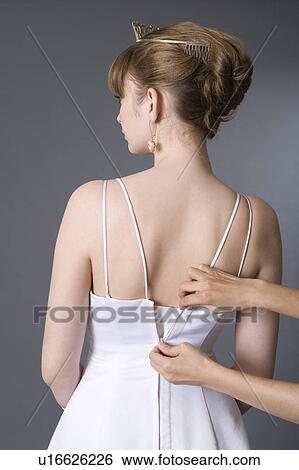 Stock Photograph - One person zipping up teenage girl's dress. Fotosearch