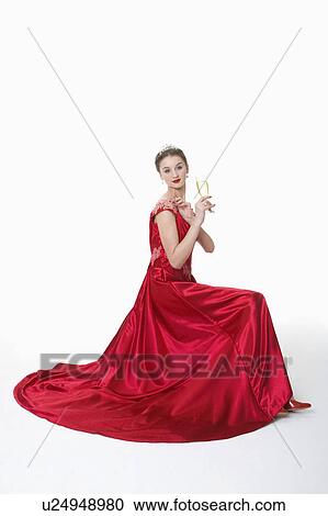 Stock Image - Teenage girl in formal dress holding a glass of beer. Fotosearch