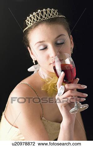 Stock Image - Teenage girl wearing formal dress holding a glass of wine. Fotosearch