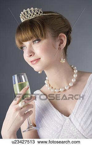 Stock Image - Teenage girl wearing jewelries holding a glass of wine. Fotosearch
