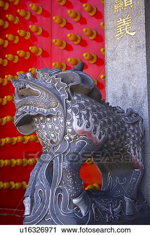 Stock Image - Lion statue by red door. Fotosearch