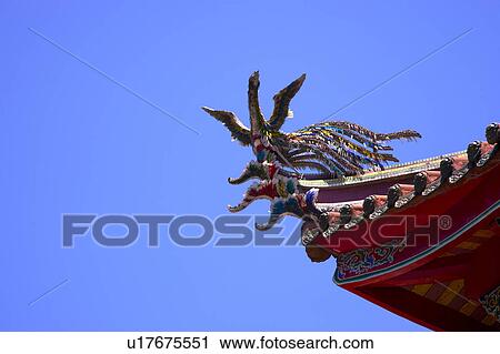 Stock Image - Phoenix sculpture on roof against sky. Fotosearch