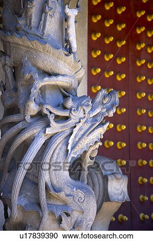 Stock Image - Stone lion statue by red door. Fotosearch