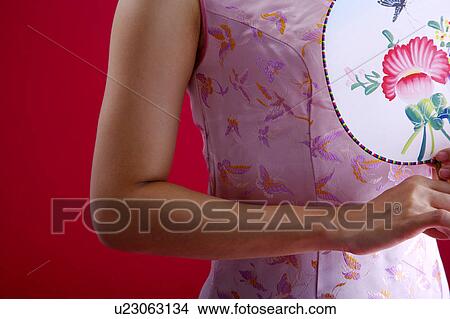 Picture - Woman in Cheongsam holding fan, mid section. Fotosearch