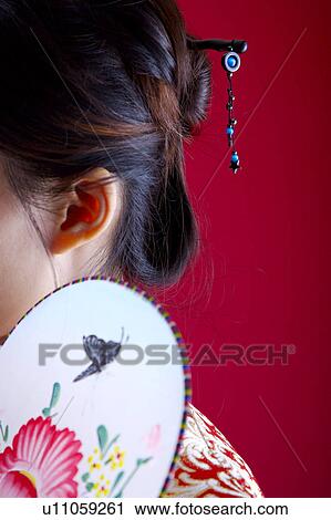 Woman with bun holding fan, close-up, side view View Large Photo Image Stock Image - Woman with bun holding fan, close-up, side view. Fotosearch