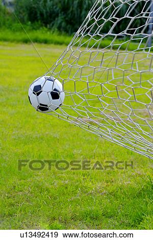 Stock Photo - Close-Up of a Football Trapped in a Goal Net on a Football Pitch. Fotosearch