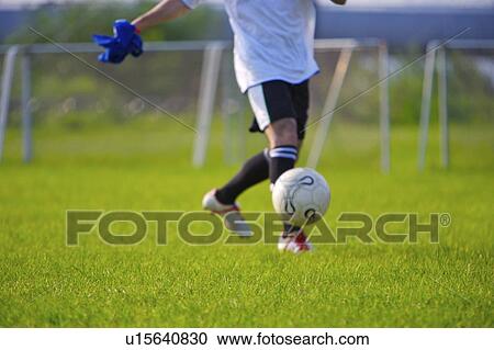 Stock Image - Football player kicking ball, mid section. Fotosearch