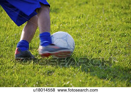 Stock Photo - Player kicking soccer ball, mid section. Fotosearch