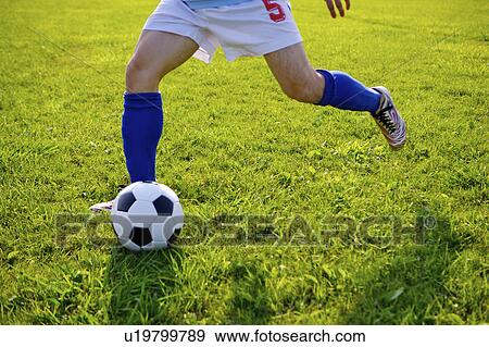 Stock Photo - Soccer player kicking ball, mid section. Fotosearch