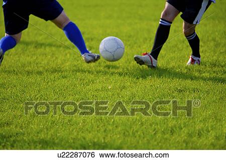 Stock Photograph - Two men playing soccer, mid section. Fotosearch
