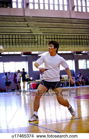 Picture - Badminton, man poised to strike shuttlecock. Fotosearch