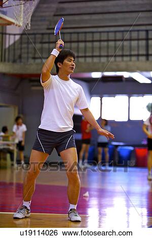 Stock Photograph - Badminton, man poised to strike shuttlecock. Fotosearch